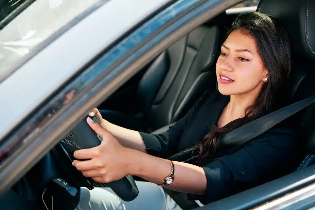 young latin woman driving luxury car